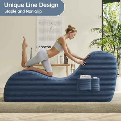 Woman using a blue exercise roller on a wooden floor with a plant and wall art in the background.